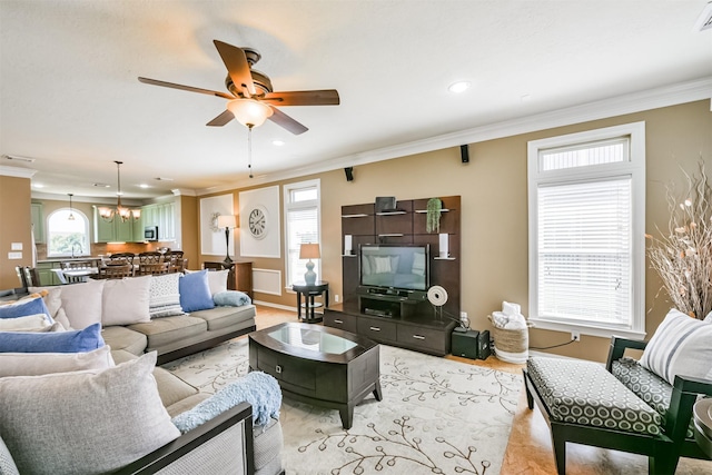 living room with ceiling fan with notable chandelier, a healthy amount of sunlight, and crown molding