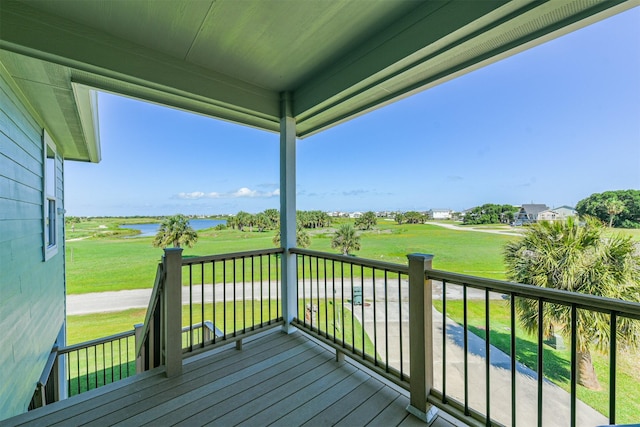 wooden terrace featuring a water view and a lawn