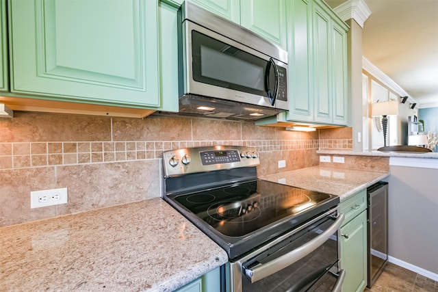 kitchen with light stone countertops, green cabinets, decorative backsplash, beverage cooler, and appliances with stainless steel finishes