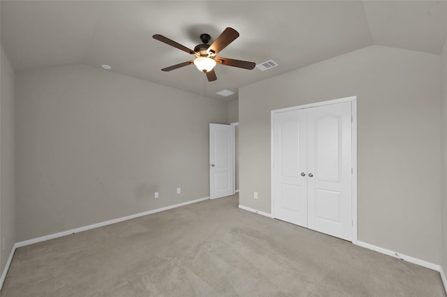 unfurnished bedroom featuring carpet, ceiling fan, vaulted ceiling, and a closet