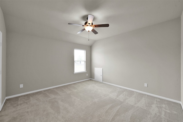 empty room featuring ceiling fan, vaulted ceiling, and light colored carpet