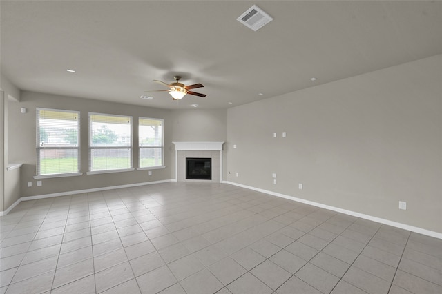 unfurnished living room featuring ceiling fan, a tiled fireplace, and light tile flooring