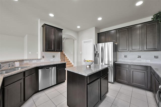 kitchen featuring appliances with stainless steel finishes, light stone countertops, tasteful backsplash, and light tile flooring