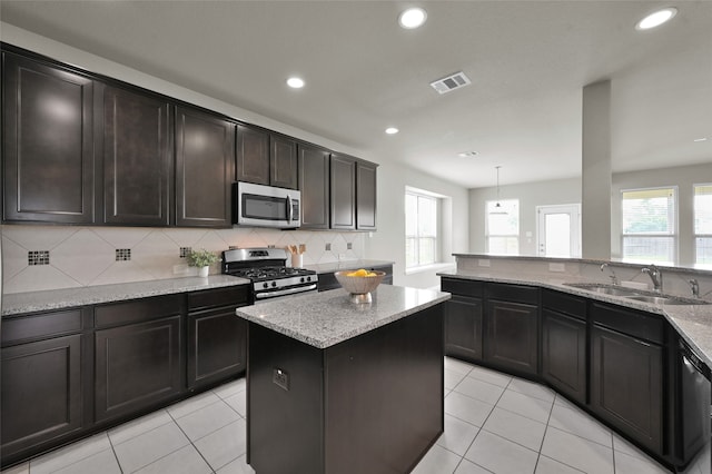 kitchen featuring light stone countertops, stainless steel appliances, backsplash, sink, and light tile flooring