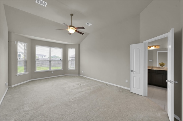 empty room featuring ceiling fan, vaulted ceiling, and light colored carpet