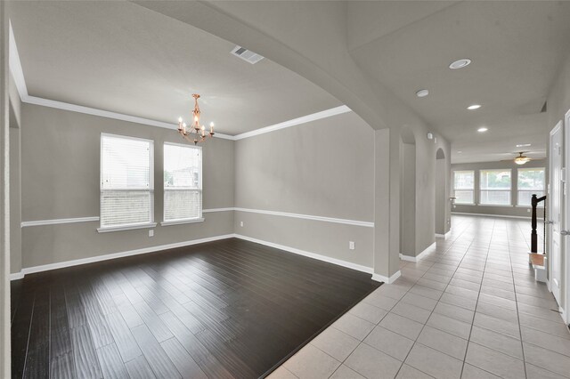 spare room featuring tile flooring, ornamental molding, and ceiling fan with notable chandelier