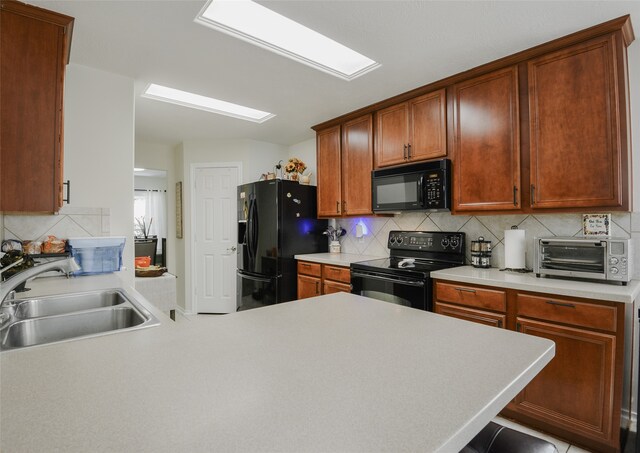 kitchen featuring black appliances, kitchen peninsula, sink, and tasteful backsplash