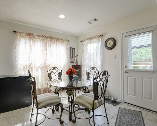 tiled dining area with a textured ceiling and plenty of natural light