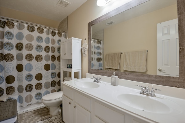 bathroom with vanity, toilet, curtained shower, and a textured ceiling