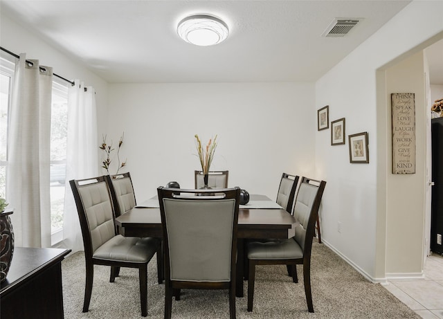 dining area with baseboards, visible vents, and light carpet