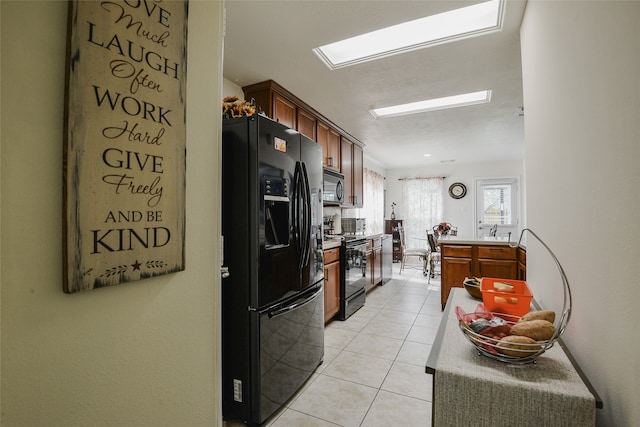 kitchen with light tile patterned floors, electric range, and black refrigerator with ice dispenser