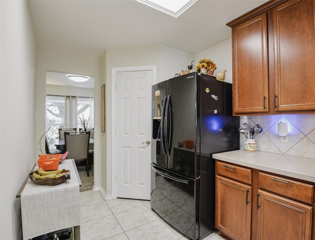 kitchen featuring light tile patterned floors, decorative backsplash, and black refrigerator with ice dispenser