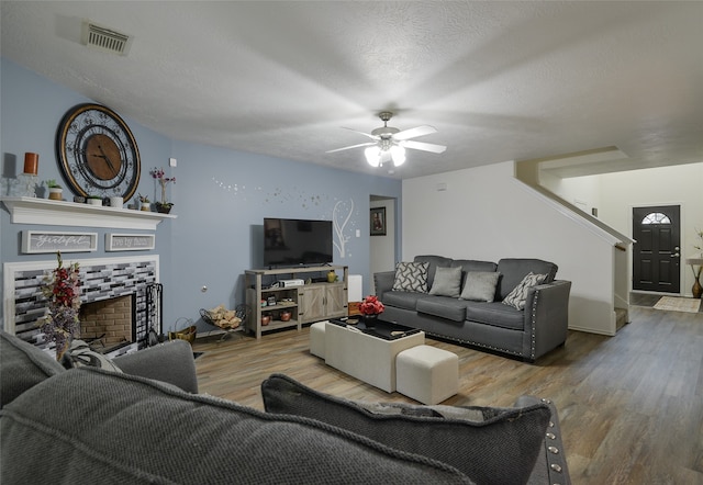 living room featuring a textured ceiling, hardwood / wood-style floors, and ceiling fan