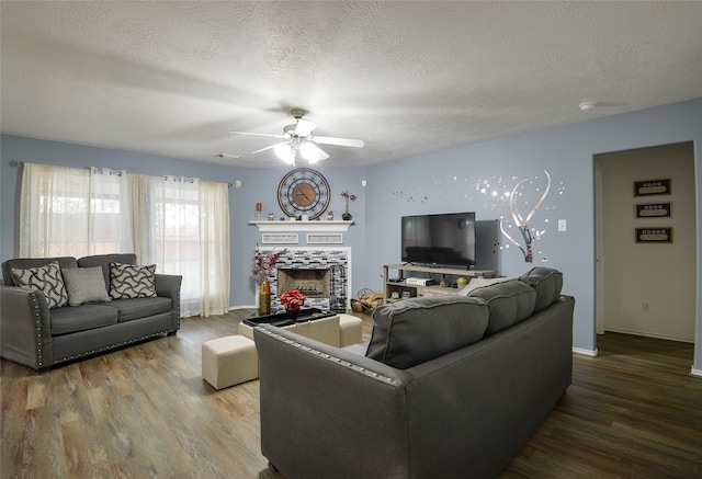 living room featuring a textured ceiling, ceiling fan, a tiled fireplace, and wood-type flooring