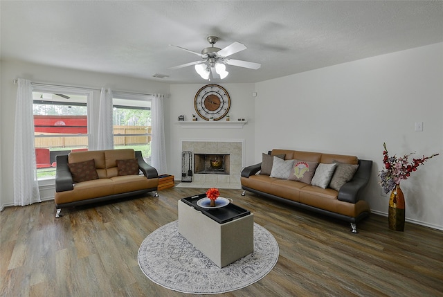 living area featuring visible vents, ceiling fan, wood finished floors, and a fireplace