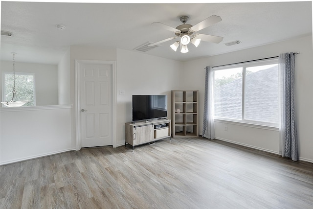 unfurnished living room featuring baseboards, ceiling fan, visible vents, and wood finished floors