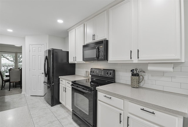 kitchen featuring light countertops, white cabinetry, decorative backsplash, and black appliances