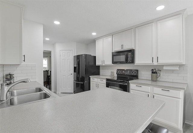 kitchen with light countertops, a sink, black appliances, and tasteful backsplash