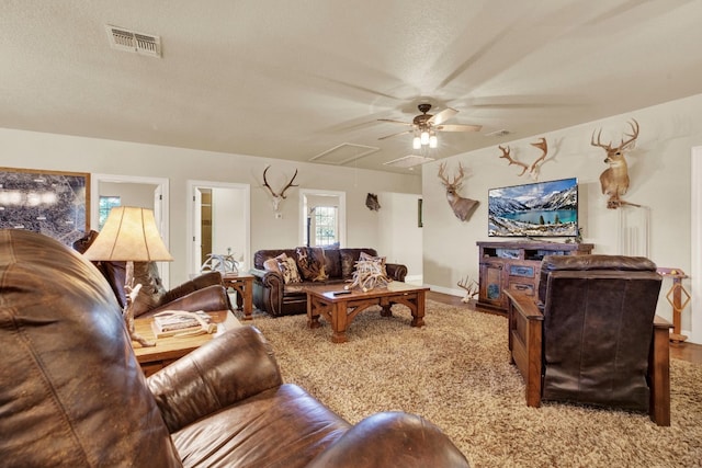 living room with ceiling fan, a textured ceiling, and carpet flooring