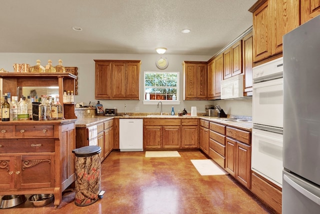 kitchen featuring sink, a textured ceiling, and white appliances