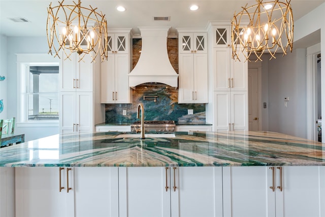 kitchen featuring a large island, pendant lighting, stone counters, and custom range hood