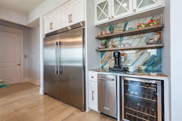 interior space with beverage cooler, stainless steel built in refrigerator, light wood-type flooring, white cabinetry, and open shelves