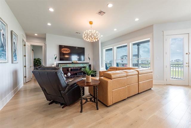 living room with a fireplace, light hardwood / wood-style flooring, and a notable chandelier