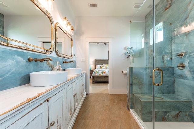 bathroom featuring a shower with shower door and vanity