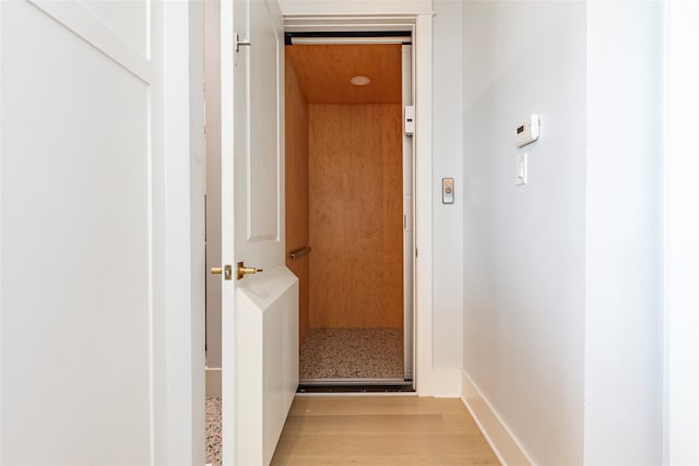 hall featuring light wood-style flooring and baseboards