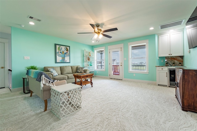 living room with beverage cooler, light carpet, and ceiling fan