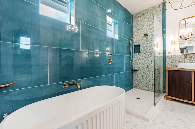 bathroom featuring marble finish floor, vanity, a freestanding tub, a shower stall, and tile walls