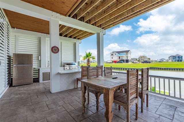 view of patio with outdoor dining area, an outdoor kitchen, a water view, grilling area, and a residential view