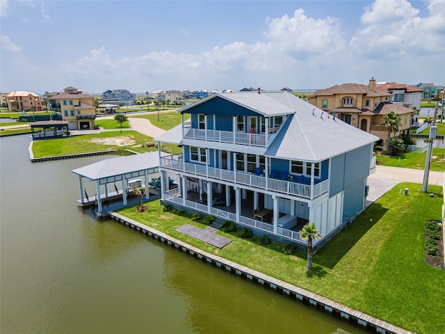 back of house with a balcony, a lawn, and a water view