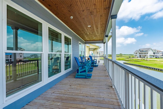 wooden terrace featuring covered porch, a water view, and a residential view