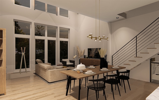 dining area with a towering ceiling, light hardwood / wood-style flooring, and a chandelier