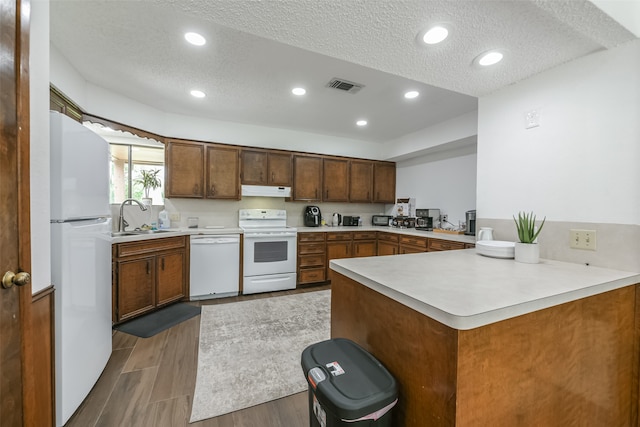 kitchen featuring kitchen peninsula, sink, ventilation hood, white appliances, and a textured ceiling