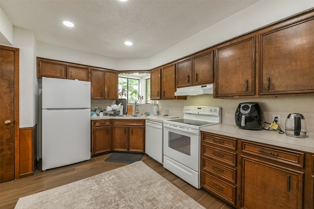 kitchen featuring dark wood-type flooring, sink, white appliances, and a textured ceiling