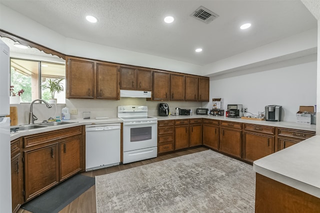 kitchen with white appliances, sink, range hood, and wood-type flooring