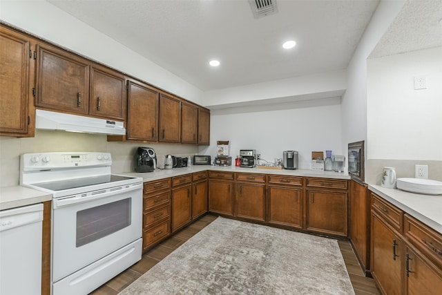 kitchen with white appliances, dark hardwood / wood-style floors, and kitchen peninsula