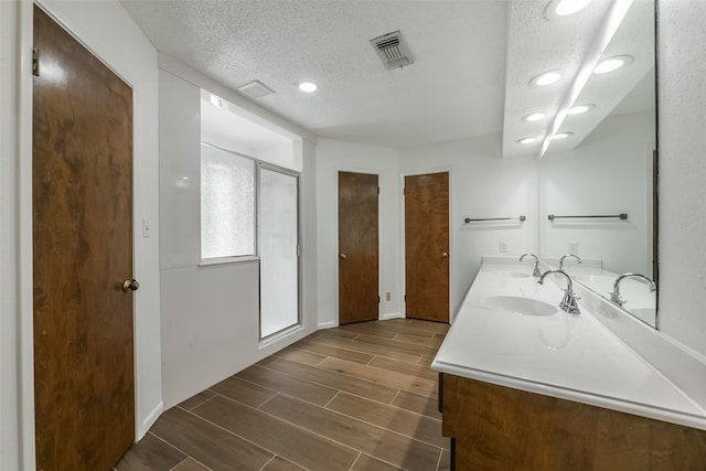 bathroom with a textured ceiling, wood-type flooring, and vanity