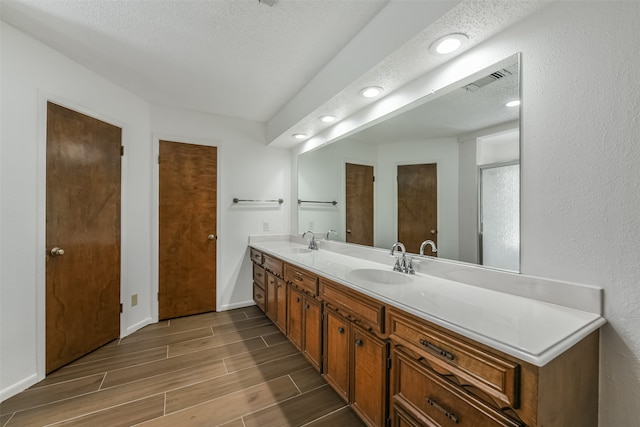 bathroom featuring dual bowl vanity and a textured ceiling