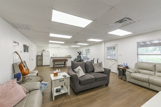 living room featuring a healthy amount of sunlight, light hardwood / wood-style floors, and a drop ceiling