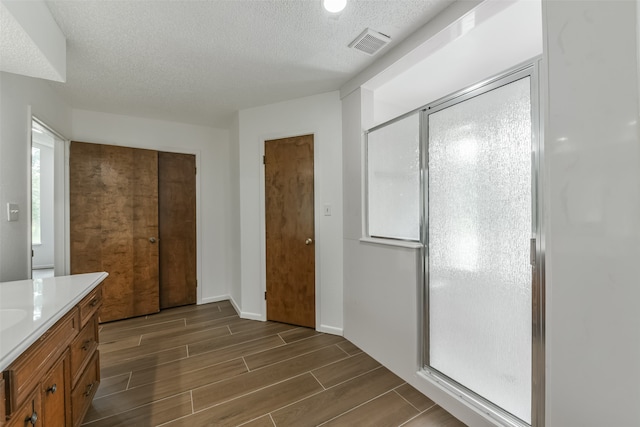 bathroom featuring a shower with door, a textured ceiling, and vanity