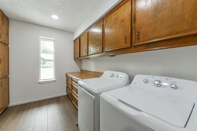 clothes washing area featuring cabinets, a textured ceiling, independent washer and dryer, and light wood-type flooring