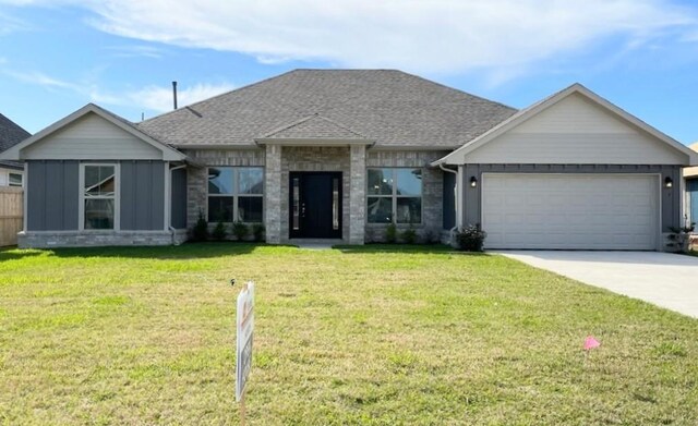 view of front facade with roof with shingles, concrete driveway, an attached garage, board and batten siding, and a front lawn