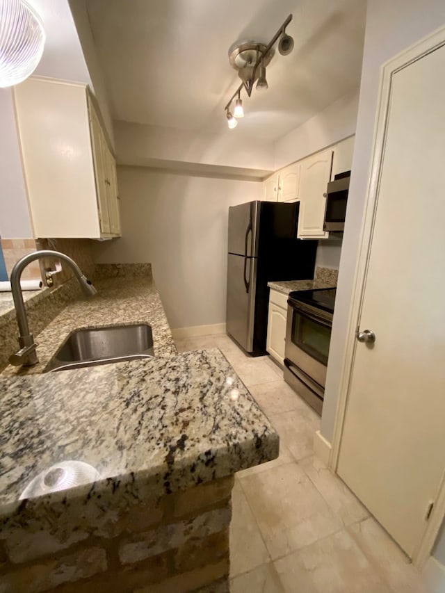 kitchen with light stone countertops, stainless steel appliances, sink, white cabinets, and light tile patterned flooring