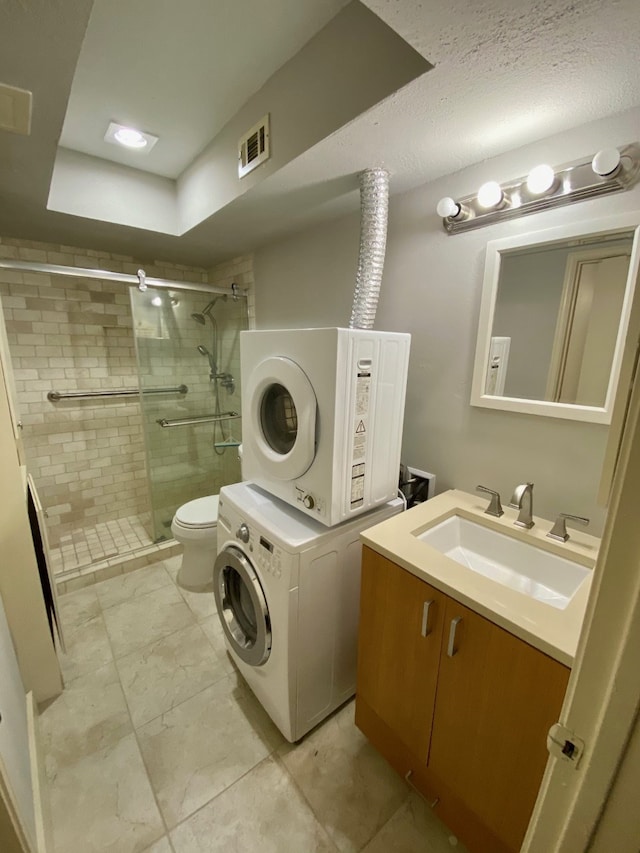 bathroom with vanity, stacked washer and dryer, toilet, and walk in shower