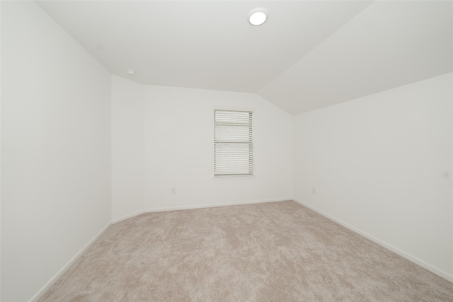 unfurnished room featuring light carpet and vaulted ceiling