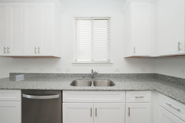 kitchen with stainless steel dishwasher, light stone counters, white cabinetry, and sink