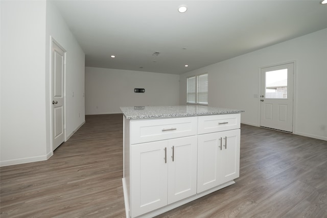 kitchen featuring white cabinets, light hardwood / wood-style floors, light stone counters, and a kitchen island